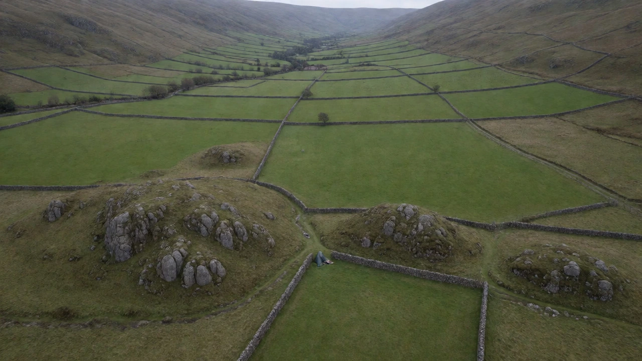 Aerial view of a tiny bivvy shelter in a remote UK valley surrounded by stone walls.